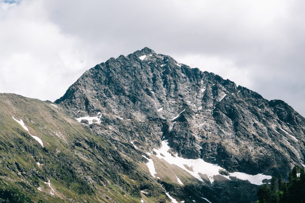 Breathtaking view of a snow-capped mountain peak under a cloudy sky, showcasing natural beauty.