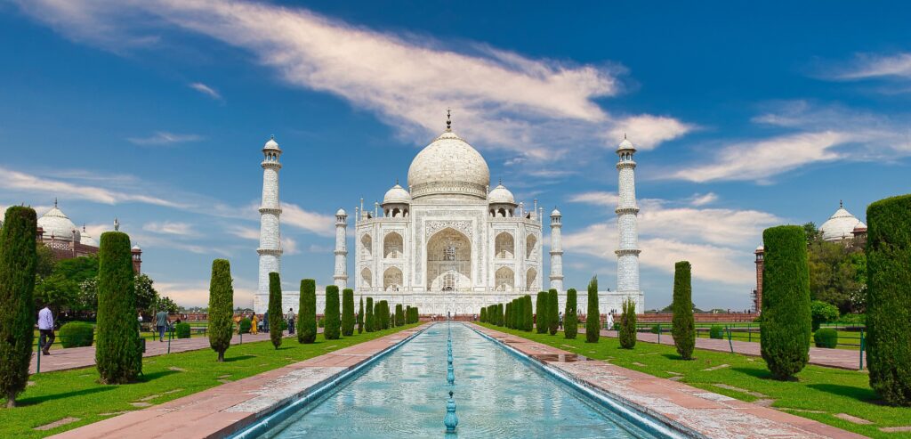Stunning view of the Taj Mahal with reflecting pool and clear blue sky. Iconic landmark in Agra, India.