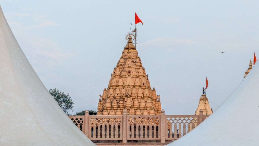 A captivating view of an ancient Indian temple with traditional flags against a clear blue sky.