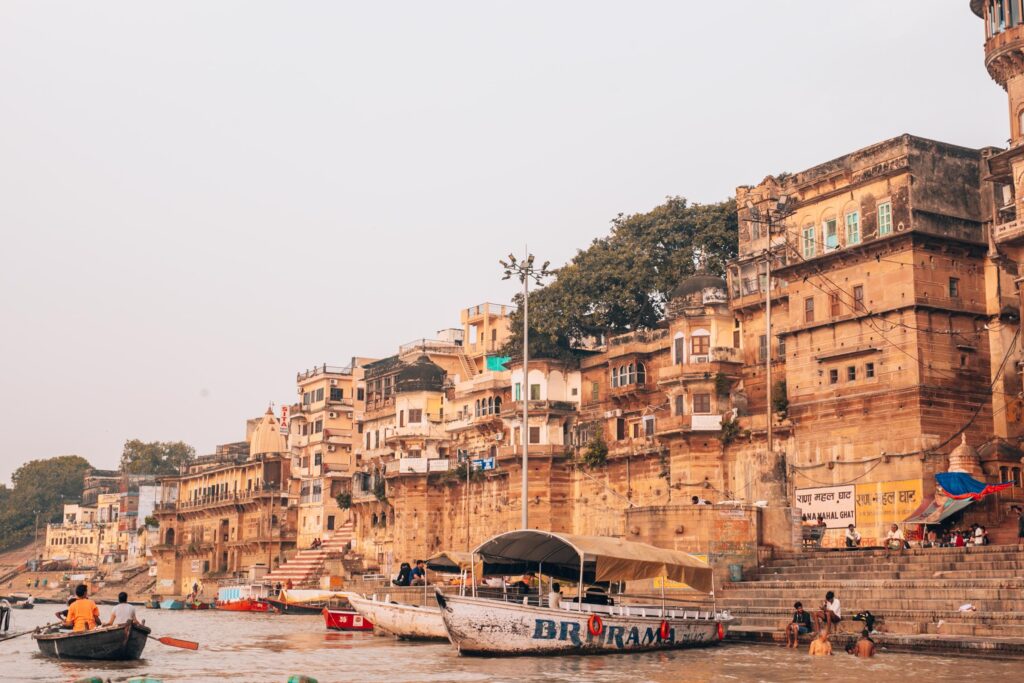 Picturesque view of Varanasi ghats along the Ganges River with bustling boats and ancient architecture.